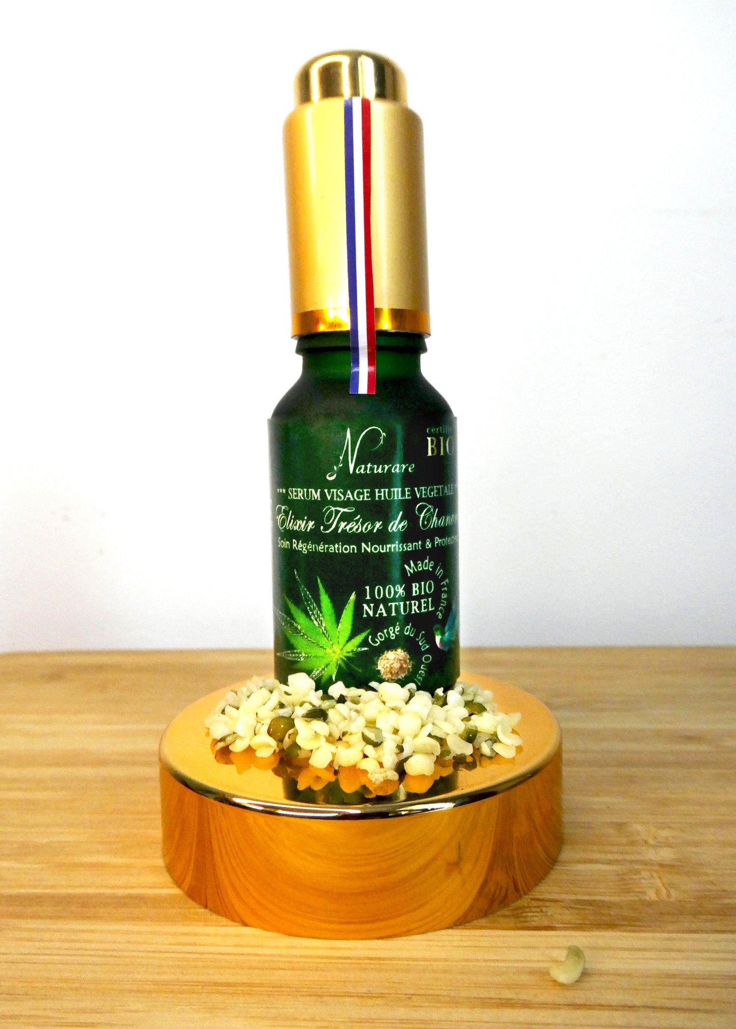Agnès' Petit Paris Skincare organic French facial serum in green bottle with gold cap on wooden stand