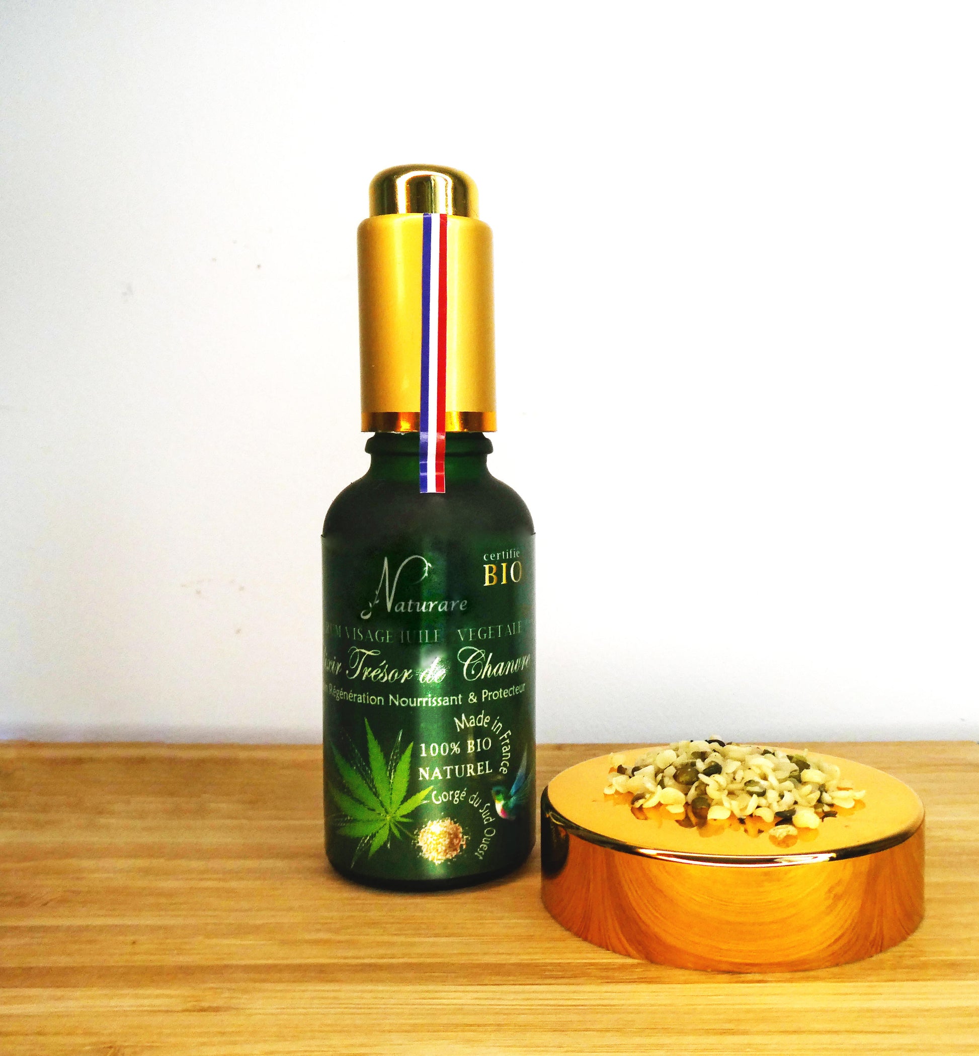 Naturare.fr anti-aging serum bottle with gold cap labeled French natural skincare elixir on wooden surface