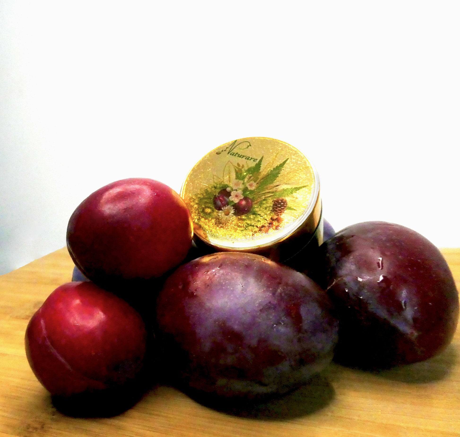 Prix PRO natural bust enhancement skincare cream by Agnes Petit Paris Skincare surrounded by fresh plums on wooden surface